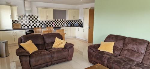 a living room with two chairs and a kitchen at Luxury apartment hawthorns in Sligo