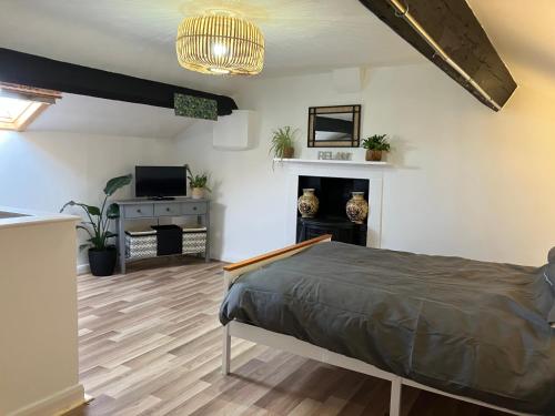 een slaapkamer met een bed, een tv en een open haard bij Bells Yard cottage in Maryport