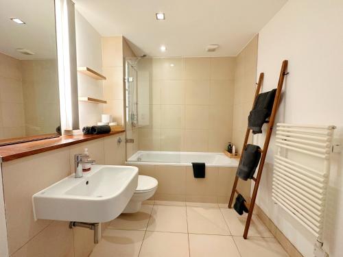 a bathroom with a sink and a toilet and a bath tub at Portobello Dock Canalside Apartment in London