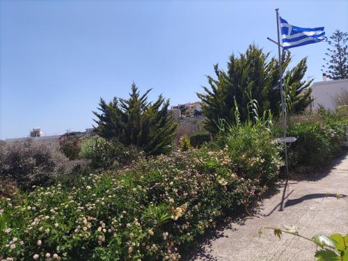 a garden with flowers and a flag in the background at Galini Rooms & Apartments in Finikas