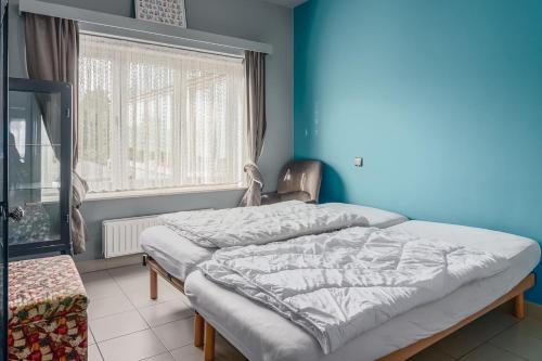 een bed in een kamer met een blauwe muur en een raam bij Hera 0101 in Koksijde