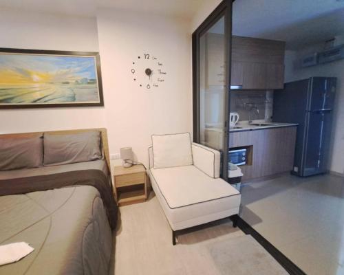 a bedroom with a bed and a chair and a kitchen at La Casita HuaHin by Tasing in Hua Hin