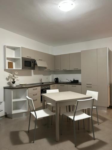uma cozinha branca com uma mesa e cadeiras em Appartamento Eugenio em Colico