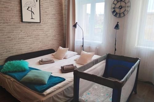 a bedroom with a bed with pillows and a clock at Przytulne studio w centrum Starego Miasta in Bydgoszcz