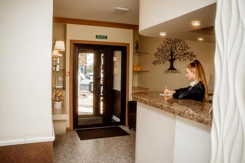 a woman sitting at a counter in a kitchen at Non-stop hotel in Boryspilʼ