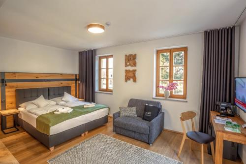 um quarto com uma cama, uma cadeira e uma televisão em Resort Valtberg Valtice em Valtice