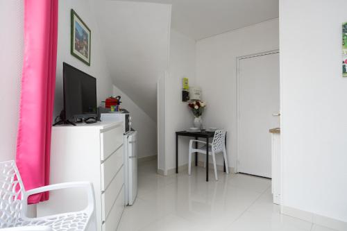 Cette chambre dispose d'une commode avec une télévision et une table. dans l'établissement Bourget RER chambre 1er étage gauche, au Bourget