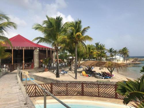 a resort with a pool and a beach with palm trees at Perle de l'Alamanda in Belle-Allée