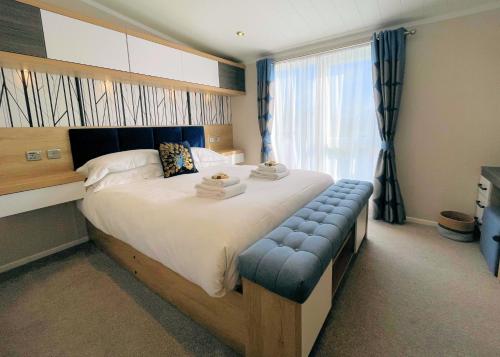 a bedroom with a large bed with a blue bench at Luxury Lakeside Lodge with HTub Beautiful Views in Annan
