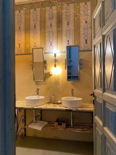 a bathroom with two sinks and two mirrors at Dimora Ferraris in Càbras