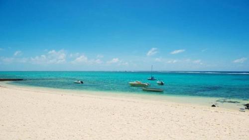 a beach with several boats in the water at Coral Bay by Dream Escapes in Blue Bay