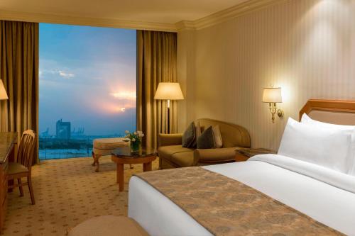 クウェートにあるSheraton Kuwait, a Luxury Collection Hotel, Kuwait Cityのベッドと大きな窓が備わるホテルルームです。