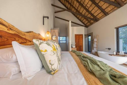 1 dormitorio con 1 cama con lavabo y bañera en Ukanyi Luxury Villa en Hoedspruit