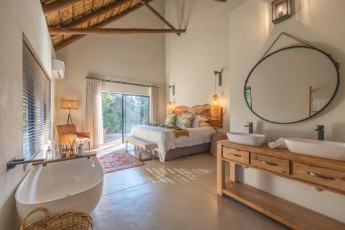 a bathroom with a sink and a mirror and a bed at Ukanyi Luxury Villa in Hoedspruit