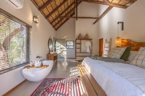 a bedroom with a large bed and a bath tub at Ukanyi Luxury Villa in Hoedspruit