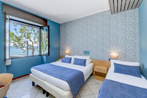 2 letti in una camera con pareti blu di Hotel Aurora a Desenzano del Garda