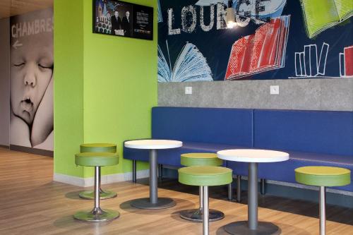 a table and stools in a room with green and blue at ibis budget Clermont Ferrand Nord Riom in Riom