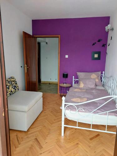 a bedroom with a white bed and a purple wall at Apartman Marija II in Omišalj