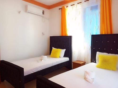 ムトワッパにあるHomestay Luxurious apartments with swimming poolの黄色い枕と窓付きのベッド2台が備わる客室です。