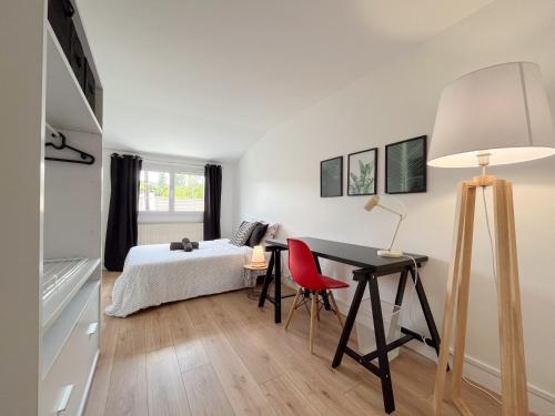 una camera con letto e scrivania con sedia rossa di Maison idéale pour visiter Paris Versailles - Chambres privées Paris-Saclay a Bures-sur-Yvette