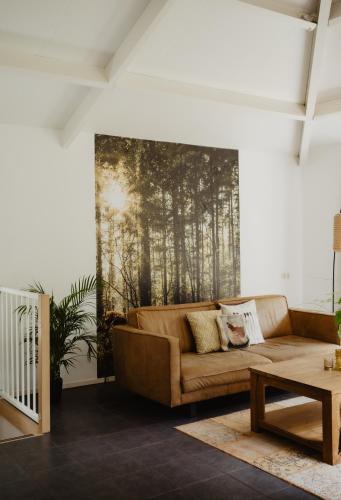a living room with a couch and a painting on the wall at Bungalow Rondomzon in Putten