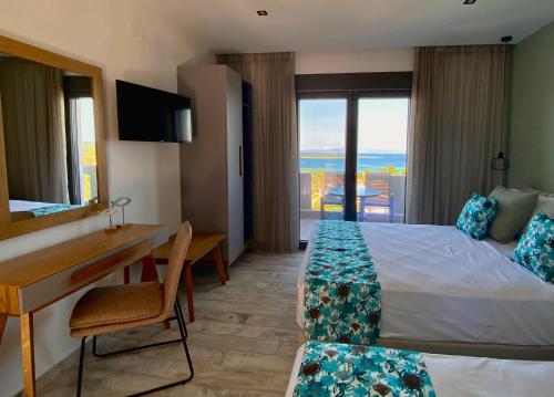 a hotel room with a bed and a desk and a window at THEA Luxury Apartments in Vourvourou