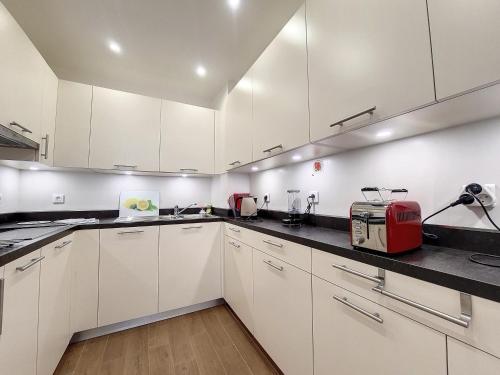 une cuisine avec des armoires blanches et un appareil rouge dans l'établissement Nestor&Jeeves - BEAUSOLEIL - Central - tres proche mer, à Nice
