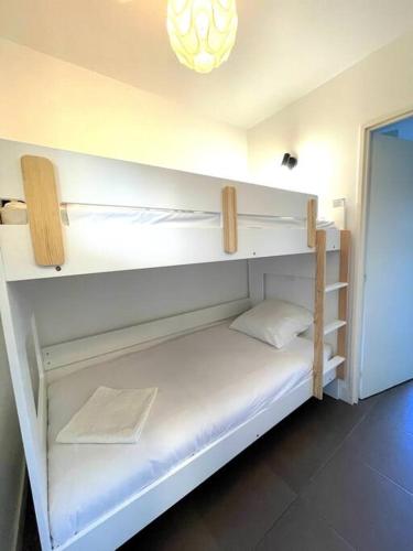 Cette chambre comprend un lit superposé avec des étagères blanches. dans l'établissement Cottage bord de mer, au Pouliguen