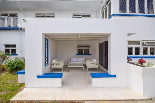 a white house with blue trim and a patio at Blue Waters 25 5 bed apts in Bridgetown