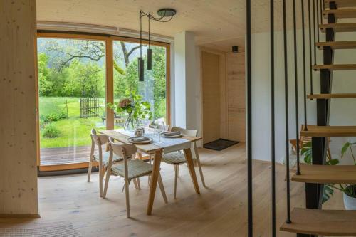 une salle à manger avec une table, des chaises et une grande fenêtre dans l'établissement Tiny Eko House Bovec, à Bovec