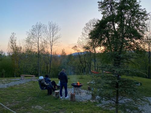 two people standing around a fire pit in a field at Casutele din Poienita in Comarnic