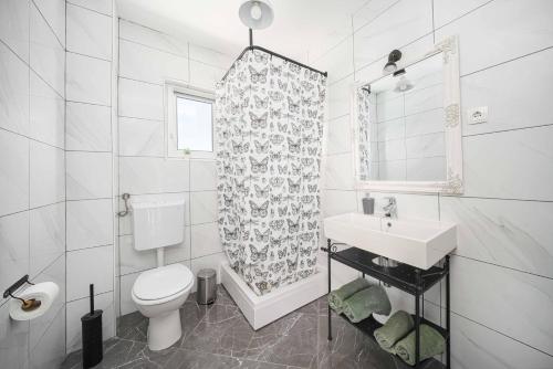 a white bathroom with a toilet and a sink at Frida Rooms and Apartments Vodice in Vodice