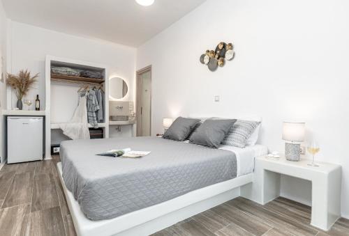 a white bedroom with a bed and a table at Naxian Air in Agios Georgios