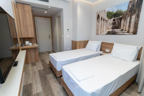 a hotel room with two beds and a tv at Titania Hotel in Sarandë