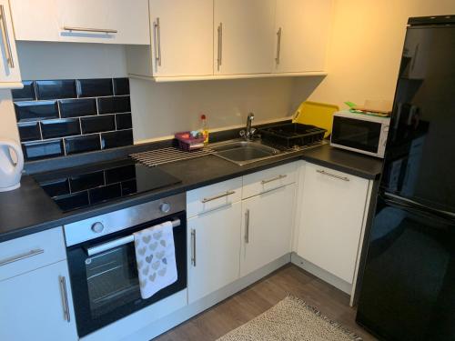 a small kitchen with white cabinets and a sink at Amazing sea views ,brilliant location Apartment in Weymouth