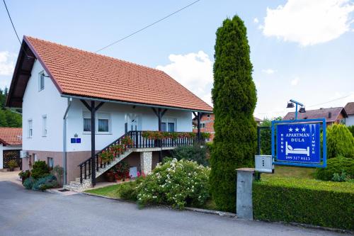 a white house with a sign in front of it at Soba i Apartman Đula in Ogulin