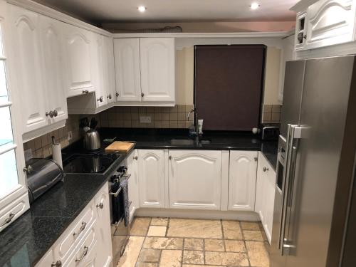a kitchen with white cabinets and a sink and a refrigerator at NEWCASTLE STUNNING SEA VIEW apartment absolute top quality over 500 of 5 star reviews You will not be disappointed in Widows Row