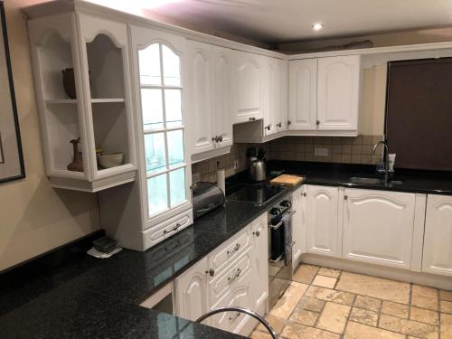a kitchen with white cabinets and black counter tops at NEWCASTLE STUNNING SEA VIEW apartment absolute top quality over 500 of 5 star reviews You will not be disappointed in Widows Row