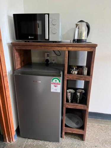 a microwave and a small refrigerator under a shelf at Koselig Homes in Nanyuki