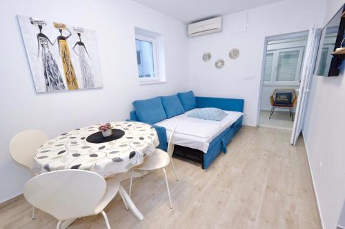 ein kleines Wohnzimmer mit einem Tisch und einem blauen Sofa in der Unterkunft Apartment Smile in Solin