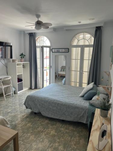 a bedroom with a bed and two windows at La casa de Lola in Caleta De Velez