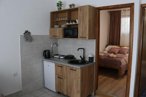a kitchen with a sink and a room with a bed at Apartman Eva in Jajce