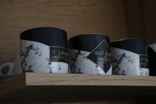 three coffee cups sitting on top of a shelf at Apartman Eva in Jajce