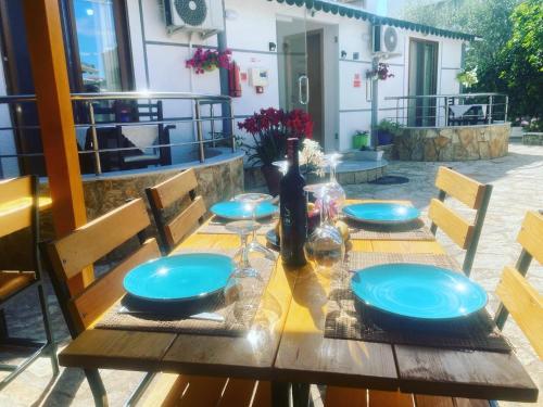 a wooden table with blue plates and bottles on it at Vila Reni & Risi in Ksamil