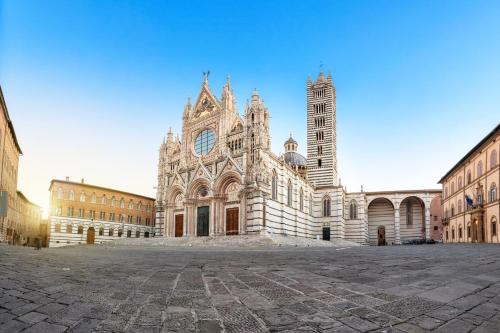 a large cathedral with a clock tower in a courtyard at Torre del Fuggisole in Siena