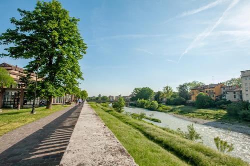 a walkway next to a river with a tree at Parma Room Station in Parma