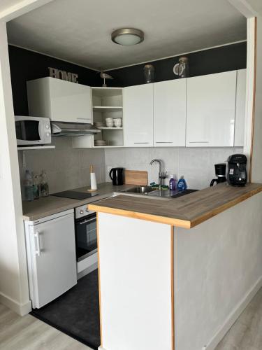 une petite cuisine avec des armoires blanches et un évier dans l'établissement Studio résidence des 3 iles proche thalasso 19, à Quiberon