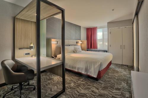 a hotel room with a bed and a desk and a mirror at SpringHill Suites Durango in Durango