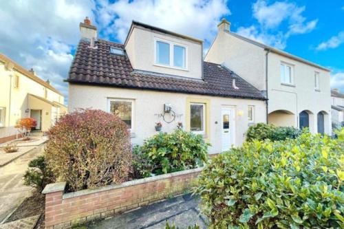 a white house with a brick fence in front of it at Cosy 2 bedroom home with free parking near city in Edinburgh