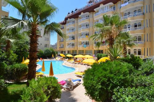 um hotel com piscina, palmeiras e guarda-sóis em Artemis Princess Hotel em Alanya